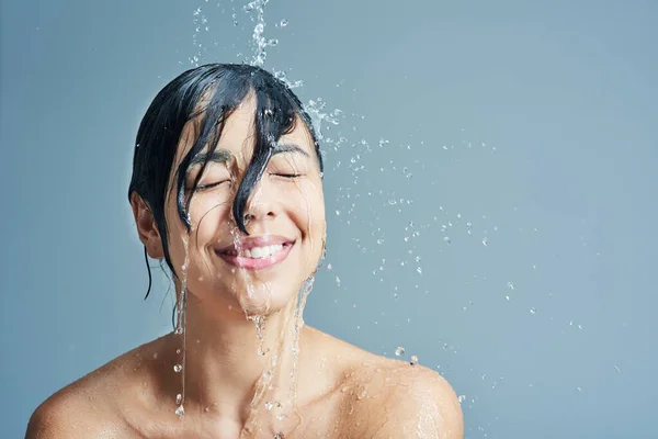 さわやかなシャワーで彼女の感覚を目覚めさせる 青い背景に爽やかなシャワーを浴びている若い女性が — ストック写真