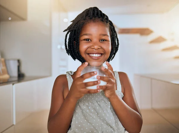 stock image Child, happy and healthy milk drink for energy vitamins or health wellness at home. Black girl portrait, glass and drinking dairy breakfast or calcium nutrition for kids teeth health care in kitchen.