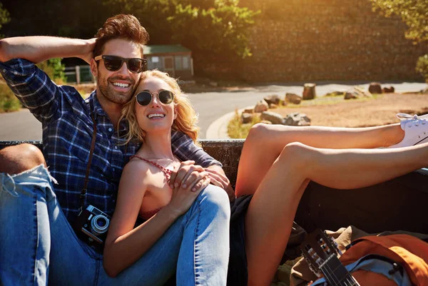 stock image Theres nothing we love more than the open road. a young couple relaxing on the back of a pickup truck while on a road trip