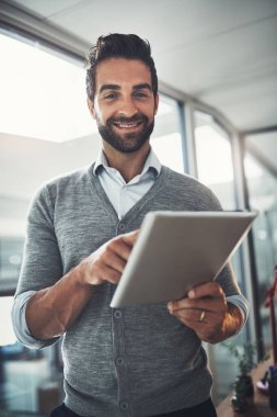 İşim her zaman dünya üzerinde bir etki bırakır. Ofiste dijital tablet üzerinde çalışan genç bir işadamının portresi.