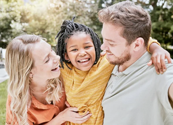 Happy family, parents and adoption kid at park, garden and nature for fun, bonding and quality time with love, care and happiness together. Smile black kid hug foster mom, dad and diversity people.
