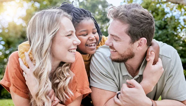 stock image Happy family, adoption and child hug parents while relax together, bonding and enjoy outdoor quality time on park field. Love, parenthood and diversity family in nature for peace, freedom and calm.