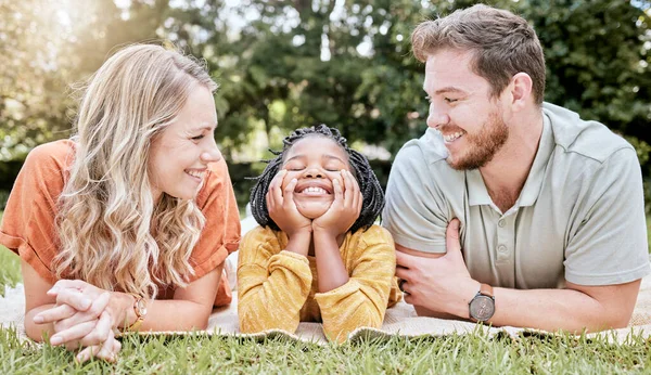 Family, diversity and children with foster parents and adopted daughter together in a park during summer. Kids, love and adoption with a mother, father and happy girl bonding outdoor in nature.