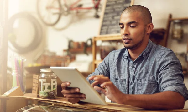 stock image Organizing his tasks on his tablet. a young entrepreneur using a digital tablet in his store