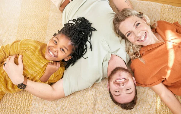 Happy, family and adoption portrait top view of caucasian mother and dad with black kid in house. Relax, interracial and smile of child together with foster mom and father in joyful home