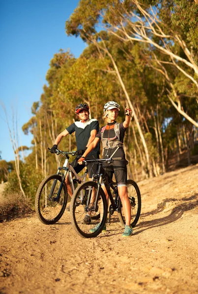 stock image Ill race you to that point. a woman pointing towards something while out for a bike ride with her boyfriend