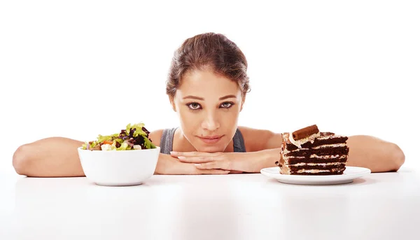 You know which one I want. Studio shot of an attractive young woman deciding between healthy and unhealthy foods
