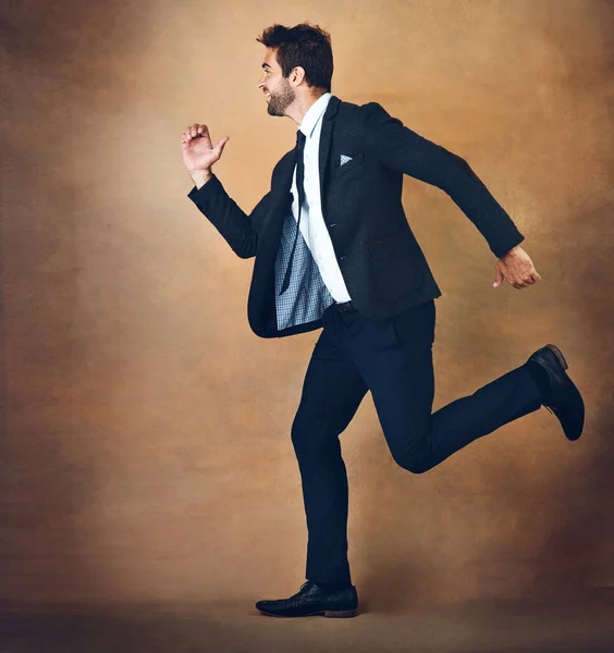 Success doesnt wait on anyone. Youve gotta run to it. Studio shot of a handsome young businessman running against a brown background