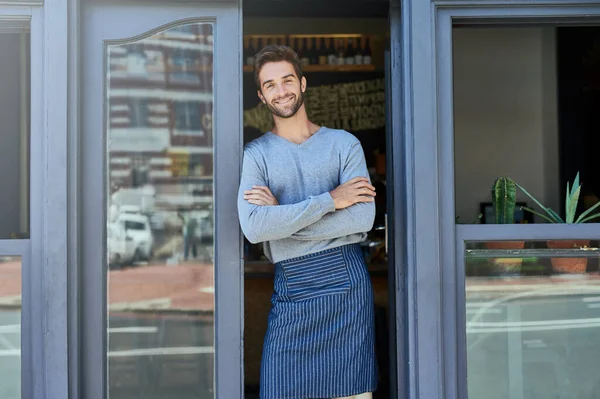 stock image His smile brings many customers through the door. a handsome and confident young man standing in the doorway of his business