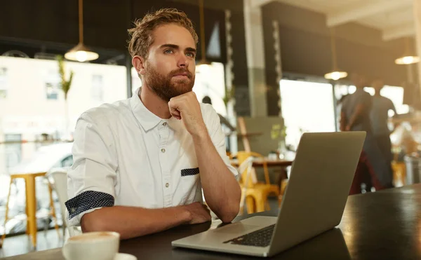 いくつかの明るいアイデアを考える カフェのノートパソコンの前に座っている若い男が — ストック写真