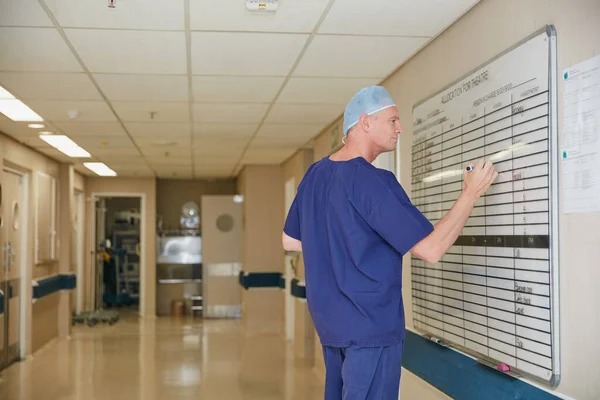毎週の回転を入力します 病院のホワイトボードに書いてある男性医師が — ストック写真