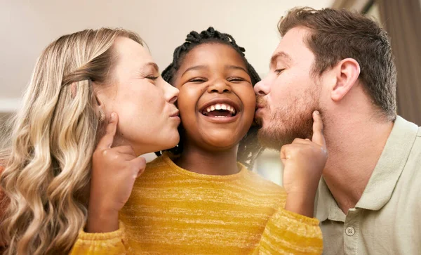 Love, foster and parents kiss daughter for adopted relationship bonding in loving, caring home. Adoption, interracial and mother and father with cheerful little girl being kissed in house.