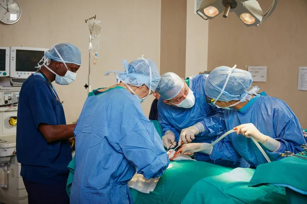 拯救生命是他们的使命 在手术室里做手术的一组外科医生 — 图库照片