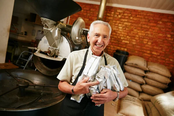 これらは私達の最もよい販売人 雄鶏で働いている間にコーヒー豆の袋を持っている高齢者の作物の肖像画 — ストック写真