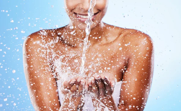 Woman hands, water splash and clean beauty, skincare and personal hygiene, wellness or shower on studio blue background. Closeup water drops, stream and washing hands for hydration, cleaning and body.