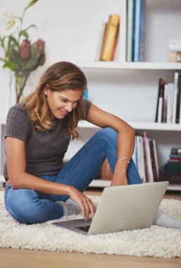 Blogları okumayı seviyor. Genç bir kadın dizüstü bilgisayarıyla evde dinleniyor.