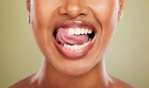 Tongue, teeth and african woman in closeup with lick, smile or happy for dental wellness in studio. Model, mouth or perfect teeth whitening for health, medical or beauty by background in healthcare.