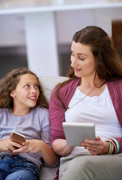 もう一人の友人からの要請だ 若い女の子と母親がソファに座ってスマートデバイスを使って — ストック写真