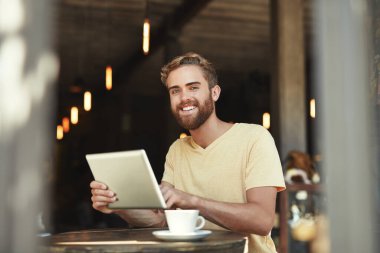 Biraz bakınmaktan zevk almak için en sevdiğim kafe. Bir kafede dijital tablet kullanan genç bir adamın portresi