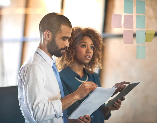 stock image Entrepreneurs doing what they do best. two young professionals brainstorming with sticky notes on a glass wall in an office