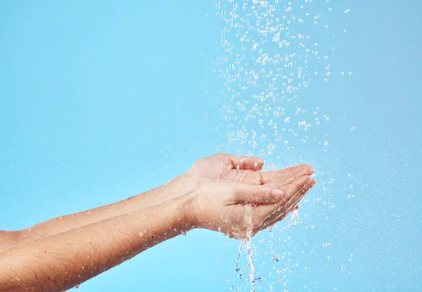 Shower, water and hands of a woman cleaning, saving and catching liquid against blue studio background. Sustainability, wellness and person with care for body, grooming and hygiene with mockup space.