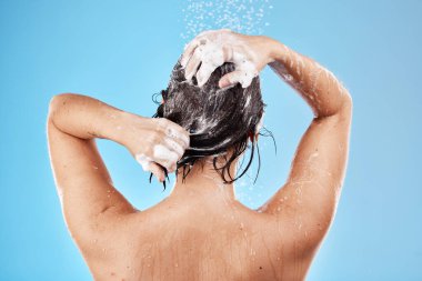 Stüdyoda temizlik yapan bir kadınla duş, saç ve şampuan saç bakımı ve hijyen için mavi arka planda. Su, sağlık ve lüks. Bakım ve tedavi için bir kadın vücudunu banyoda yıkıyor..