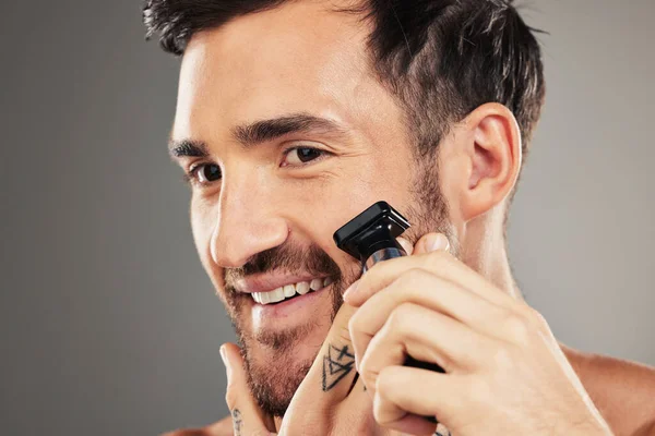 Face, skincare and man shaving with razor in studio isolated on gray background mockup. Smile, wellness and happy male model from Australia shave beard or facial hair for grooming, beauty or hygiene.