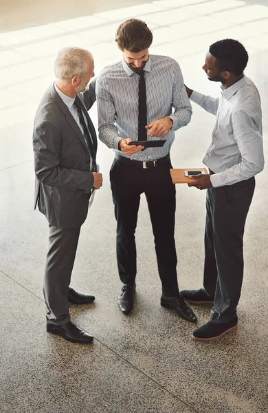 stock image He never fails to impress in the office. High angle shot of a group of businessmen talking together while standing in an office lobby