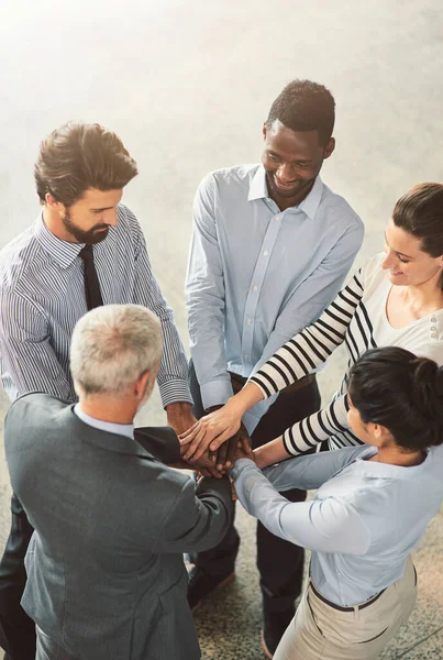 Lets do this team. High angle shot of a group of businesspeople standing in a huddle together in an office lobby