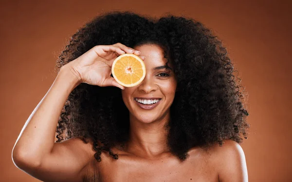 Orange, skincare and beauty of a black woman holding health, vitamin c and healthy fruit. Portrait of a model with skin wellness, cosmetic eye treatment and diet food with a happy woman face.