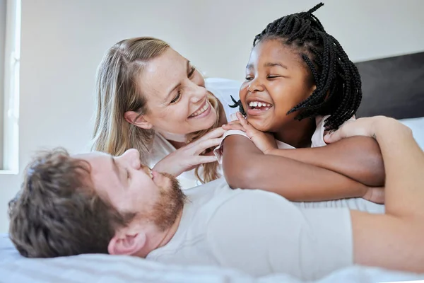 Relax, adoption and diversity with family in bedroom for happy, support and bonding in the morning. Wake up, smile and playing with foster care child and parents at home for affection, trust or funny.