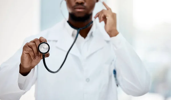 Black man doctor, stethoscope in hand and health with medical and check up in hospital. Healthcare, health insurance and professional in medicine, surgeon listening to heartbeat and cardiology