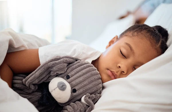 Peace, morning and wellness of black child sleeping in cozy bed with toy teddy in home on the weekend. Relax, sleep and health of kid dreaming in comfortable home bedroom with teddy bear