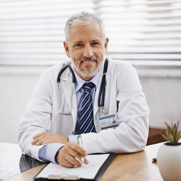 Here to get you healthy with the most effective treatment. Portrait of a mature male doctor sitting at his desk