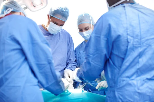 Saving lives. Surgeons performing surgery in an operating theatre