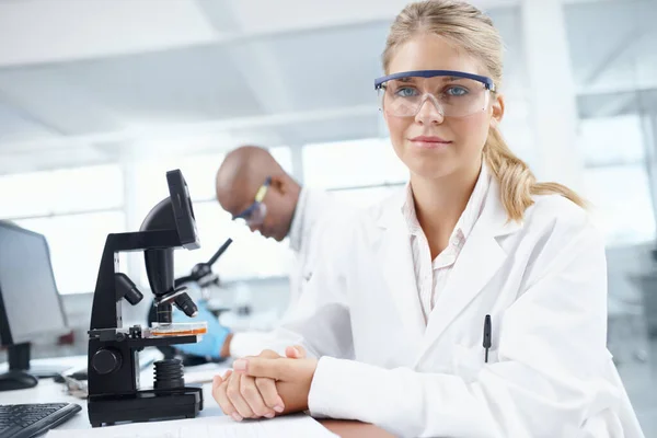 科学は嘘をつかない 背景に男性同僚と顕微鏡の前で豪華な女性科学者の肖像画 — ストック写真