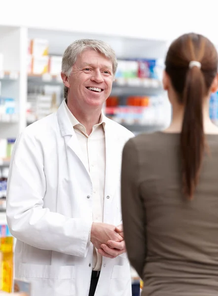 薬剤師と顧客との会話 ドラッグストアでの顧客との会話の成熟した薬剤師の肖像 — ストック写真