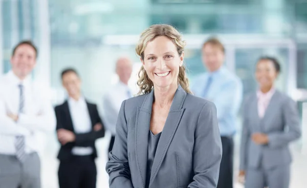 stock image Shes broken the glass ceiling. Smiling mature businesswoman with her business team behind her - portrait