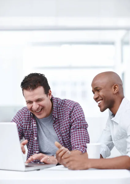 Teamwork can be fun. Two cheerful businessmen working together on a project on a laptop
