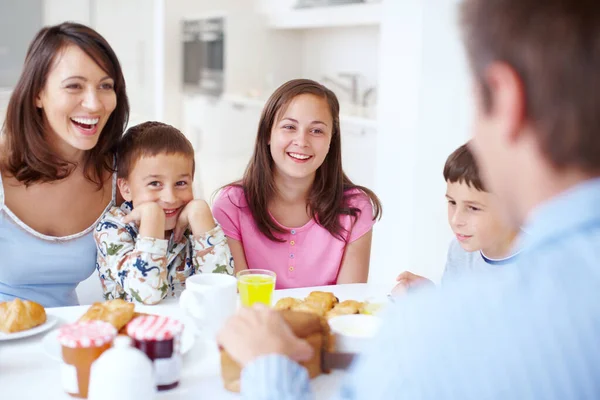 食欲をそそる朝食の周りに笑い 幸せな家族は朝食時にキッチンテーブルに座っています — ストック写真