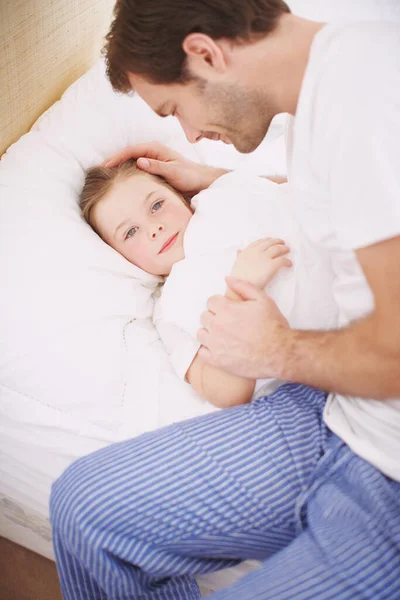 She loves it when dad puts her to bed. A dad lovingly putting his daughter to bed