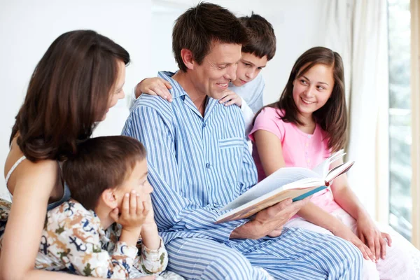 Bonding and learning with a good book. A loving family of five reading on a bed together