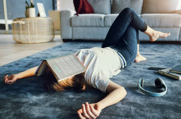 Stock image Education, tired and book with a woman student lying on the floor of her living room, sleeping in a home. Learning, exhausted and reading with a female college pupil asleep in a house while studying.