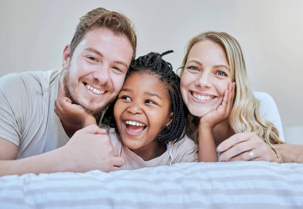 Diversity, happy family or foster parents in bedroom relax, happy or family love portrait in house or home. Mother, father and black girl with smile on bed for happiness, quality time or support.