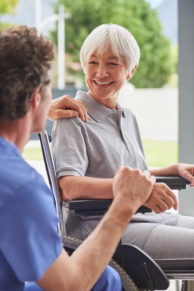 在全面恢复的路上 坐在轮椅上与医生交谈的一位快乐的老年妇女 — 图库照片