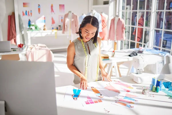 Fashion designer, drawing and asian woman, creative sketch of clothes and industrial tailor manufacturing in textile startup studio. Happy woman, artist and illustration, paper and color swatch ideas.