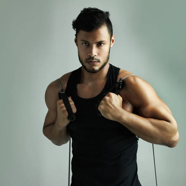 stock image Training hard to be the best. Studio shot of a young man working out with a resistance band against a gray background