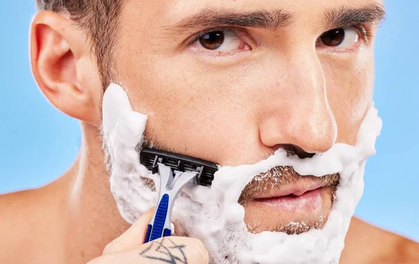 Shaving face, hair removal and man with razor in grooming and hygiene portrait, cream on beard to clean and beauty with studio background. Foam, moisturizer and cleaning with skincare and wellness