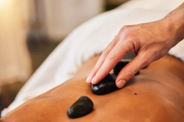 Hot stone massage, spa and skincare for wellness, health and physical therapy to relax in luxury. Mind, body and spirit wellness with rock therapy on skin in closeup with oil, zen or natural cosmetic.