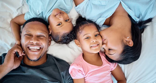 stock image Happy family, love and relax in bed together for support, care and quality time bonding. Parents, children and mom kiss girl face for affection, happiness and beautiful portrait in family home.